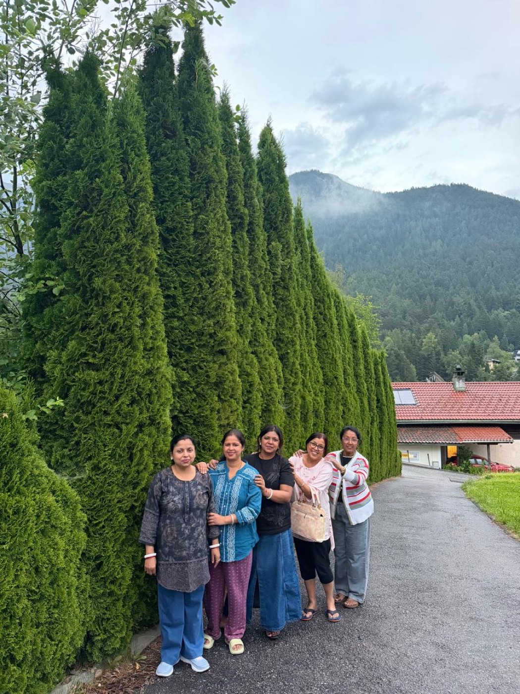 Five travellers on a lane below forested mountains in an alpine village